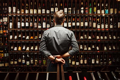 bartender at wine cellar full of bottles with exquisite drinks